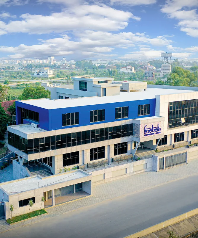 Aerial view of a Froebel’s International School campus with a blue-clad upper floor and glass frontage.