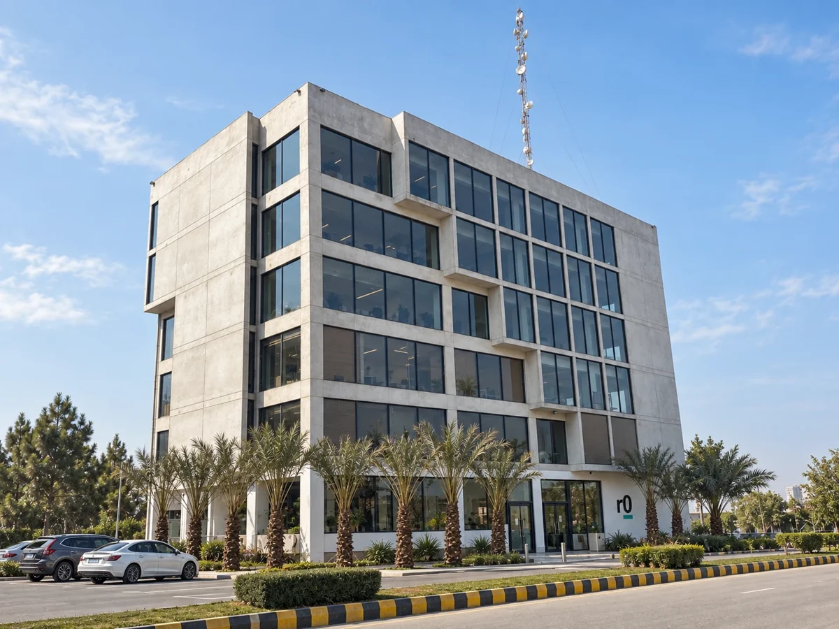 The Release Zero office building: a six-storey concrete and glass building with an r0 sign at the entrance, lined with palm trees.