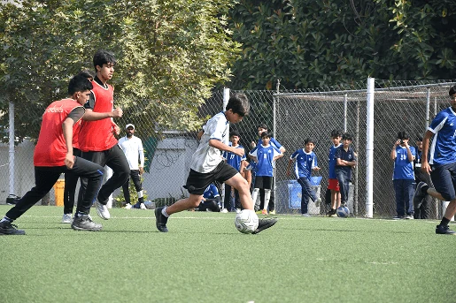 Students playing a football match on the school pitch.