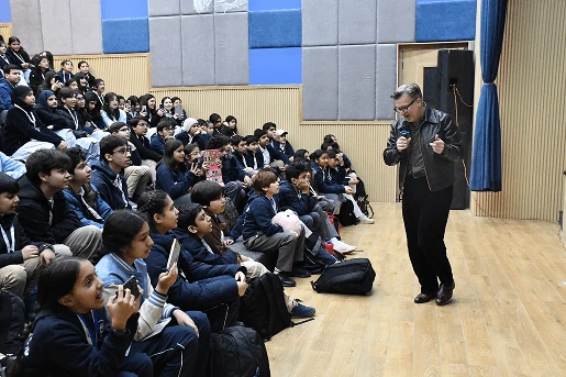 A guest speaker talking with students in the school auditorium.